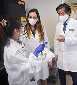 Lab scientist Sidney Huang, left, consults with microbiology lab director Dr. Cassiana Bittencourt, center, and Dr. Edwin S. Monuki, head of UCI Health Pathology & Laboratory Services.