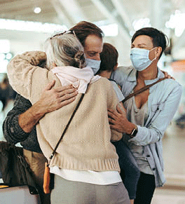 Grandmother hugging arriving family at the airport.