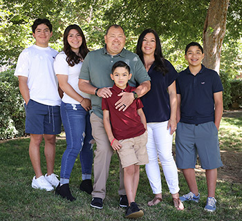 Sean Ramos, center, and his family pose at a Riverside park for a family portrait of this UCI Health bone marrow transplant patient.