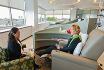 A patient talks with a guest during treatment at UCI Health Cancer Center — Newport's new infusion center.