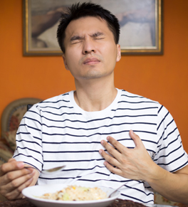 man eating and having heartburn