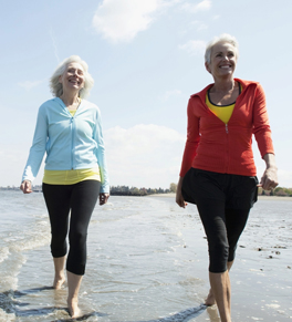 two women walking on beach smiling