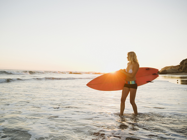 woman with surfboard getting vitamin d from sun