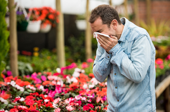 man sneezing in a flower shop