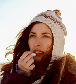 woman in winter putting on lip balm