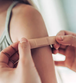 caregiver puts bandage on a girl's arm