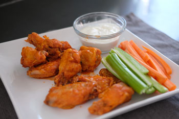 baked chicken wings in hot sauce with carrots and celery