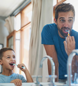 father and son brushing teeth together in bathroom