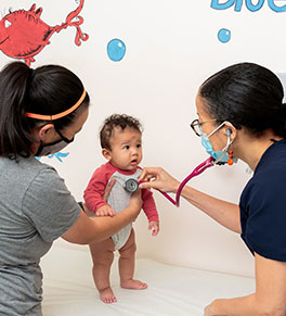 UCI Health pediatrician Dr. Candice Taylor listens to Nathan Le's heartbeat as his mother, Pauline Le, holds him.