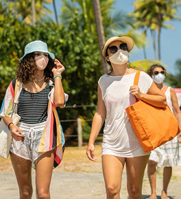 Young women stroll near the beach wearing masks to protect against COVID-19.
