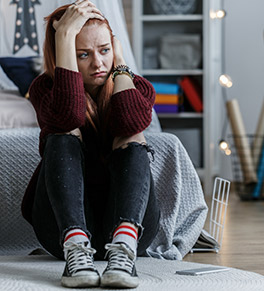 Upset teenager holds her head in her bedroom.