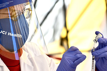 UCI Health nurse prepares COVID-19 vaccine for patient.