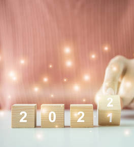 2021 spelled out on wood blocks with sparkles and a finger ready to flip it to 2022.