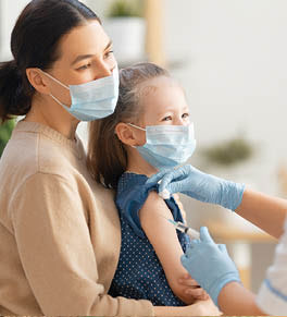 Mom holds young daughter as she gets COVID-19 vaccine shot.