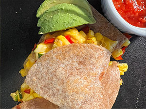 Egg and veggie breakfast quesadilla with avocado slices and salsa