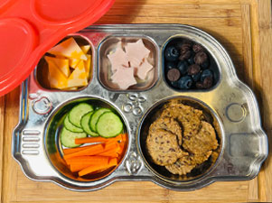 A DIY lunchable with meat, cheese, crackers, fruits and vegetables.