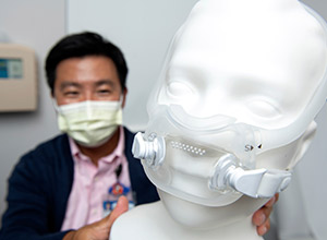 UCI Health sleep specialist Dr. KyoungBin “Kevin” Im displays one of the breathing masks used to treat sleep apnea.