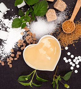 A mix of artificial and natural sweeteners are displayed on a black background.