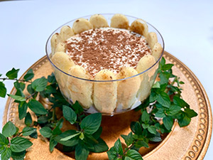Tiramisu trifle on a gold platter with fresh mint garnish.