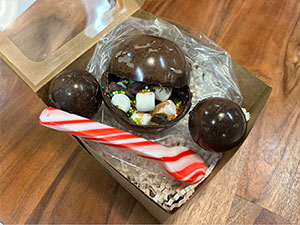 Three chocolate bombs in a gift box with peppermint candy spoon.