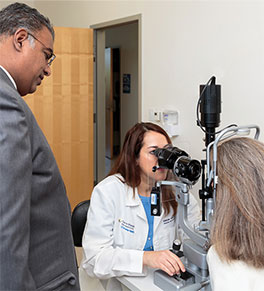 Dr. Mitul Mehta watches Dr. Marjan Farid perform an eye exam on a patient.