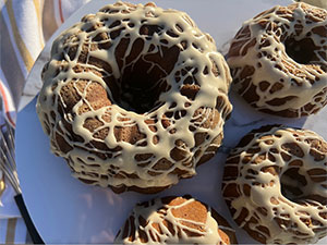 Various sizes of gingerbread Bundt cakes topped with maple glaze are displayed on a platter.