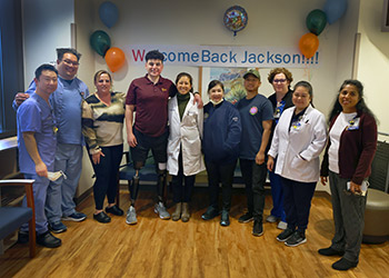 The burn and trauma teams pose with double-amputee Jackson Gutierrez and his mother, Maureen Congelosi-Gutierrez, third from left, during a reunion celebration at the UCI Regional Burn Center. width=