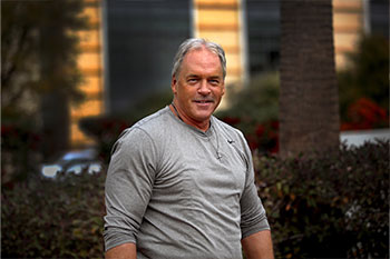 James Kazak, a colorectal cancer survivor, is looking fit and healthy in a gray long-sleeved t-shirt.