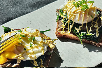 Spinach Mushroom Toast with Poached Egg and Yogurt Tahini Sauce displayed on a gray plate.