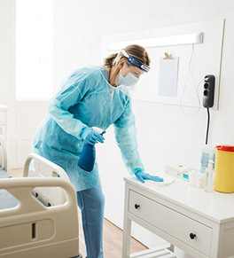 A staff member disinfects a hospital room.