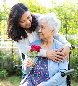 younger woman giving elderly woman in a wheelchair a hug; lisa gibbs shares tips for preventing sundowning