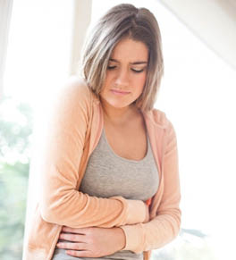 Young woman holding her stomach because of IBS pain.