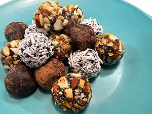 A variety of chocolate truffles displayed on turquoise plate.