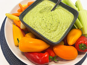 White bean and spring peas dip with roasted shallots displayed with raw celery, carrots and baby peppers.