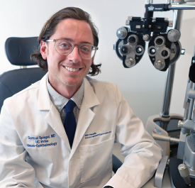 UCI Health neuro-ophthalmologist Dr. Samuel Spiegel sitting near eye exam equipment.
