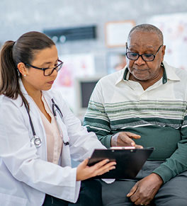 Older Black man consults with Asian physician.