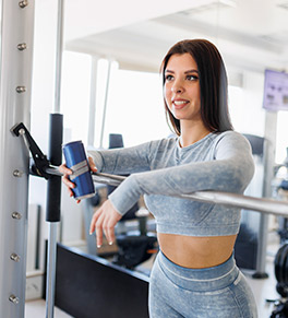 Young woman in a fitness gym holds an energy drink.
