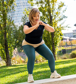 An overweight woman is exercising in a park.