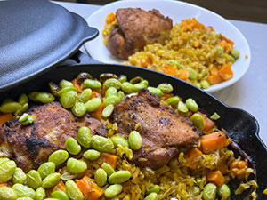 One pan turmeric chicken shown in cast iron skillet and also plated in the background.