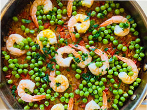 Colorful holiday shrimp paella is served in a tarnished metal bowl.