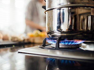 Blue flame of gas stove burner under stainless steel pot.