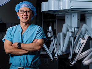 UCI Health urologist Dr. David I. Lee stands beside a robotic system that enables him to perform precision surgery for prostate cancer.