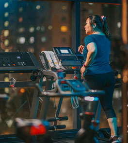 asian woman walking on treadmill in the evening in a gym