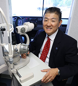 UCI Health pediatric ophthalmologist Dr. Donny Suh is seated in the eye mobile ready to give an exam.