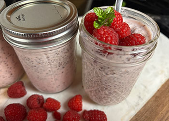 Vanilla raspberry chia pudding served in mason jars with fresh raspberry and mint garnish.