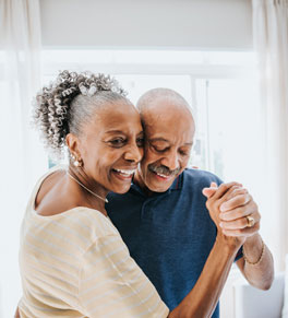 older african american couple dancing in a well-lit room with plants at home having fun and connecting to protect  memory