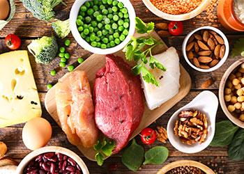 A variety of animal- and plant-based protein foods arrayed on a wood board.