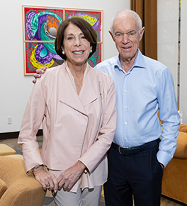 Sue and Ralph Stern stand in a room with a colorful painting in the background.
