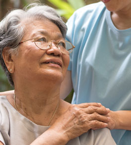 filipino woman with parkinsons disease holds the hand of a caregiver