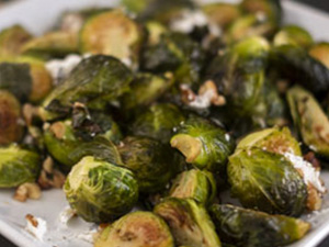 Brussel sprouts with goat cheese and walnuts is displayed on a white platter.